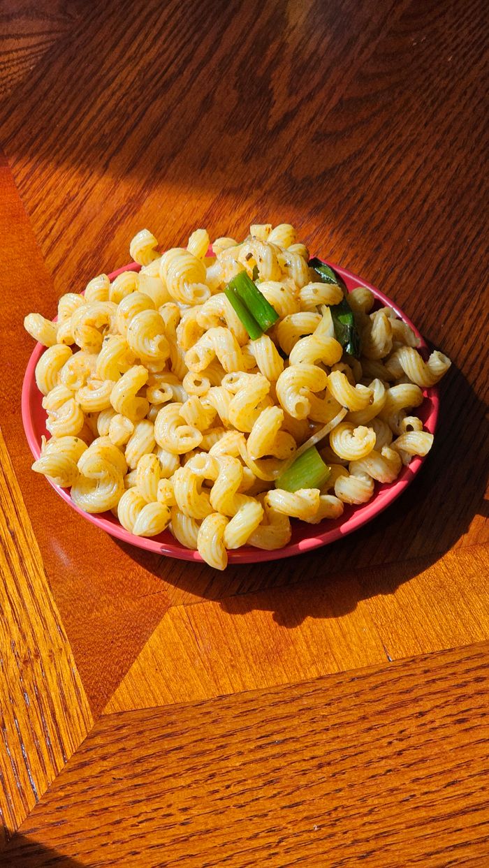 Freshly cooked seasoned cavatappi pasta in a bowl on a wooden table.